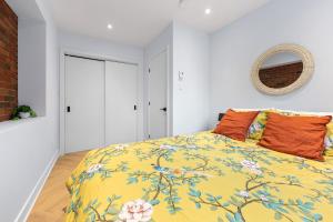ein Schlafzimmer mit einem Bett mit einer gelben Decke und orangefarbenen Kissen in der Unterkunft Le Karina - Vieux-Terrebonne in Terrebonne