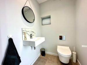 a bathroom with a sink and a toilet and a mirror at Brand New 4 Bedroom House -Sleeps 9 - Free Parking - Great Location - Fast WiFi - Smart TV - Close to Poole & Bournemouth & Sandbanks in Poole