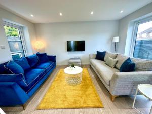 a living room with a blue couch and a tv at Brand New 4 Bedroom House -Sleeps 9 - Free Parking - Great Location - Fast WiFi - Smart TV - Close to Poole & Bournemouth & Sandbanks in Poole