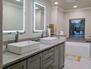 a bathroom with two sinks and a tub and a mirror at Gorgeous Plano Home ~ Private Backyard Pool Oasis in Plano