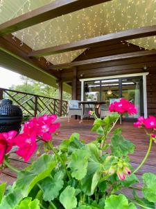 eine Veranda mit rosa Blumen auf einer Holzterrasse in der Unterkunft Rubikiai Lux Ežero Namelis in Aniūnai