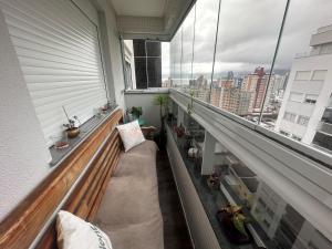 a balcony with a couch and a large window at Apartamento no Estreito in Florianópolis