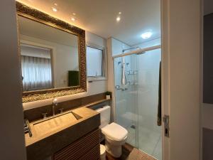 a bathroom with a toilet and a sink and a mirror at Apartamento no Estreito in Florianópolis +26 photos