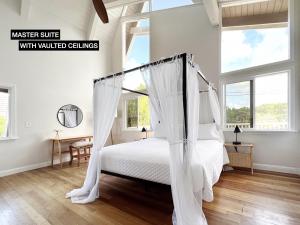 1 dormitorio con cama con dosel y cortinas blancas en Anahola Aloha Beach House home, en Anahola