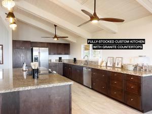 a large kitchen with wooden cabinets and a ceiling fan at Anahola Aloha Beach House home in Anahola