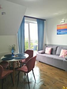 ein Wohnzimmer mit einem Sofa, einem Tisch und Stühlen in der Unterkunft Apartamenty WIKTORIA morska18 in Kuźnica