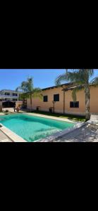 a swimming pool in front of a building with palm trees at Villa Letizia in Anzio