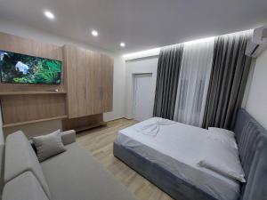 een slaapkamer met een bed, een bank en een tv bij SOLE INN in Vlorë