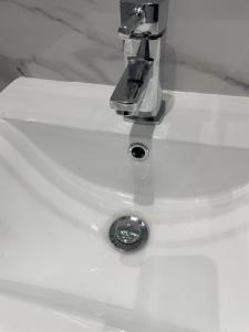 a white bathroom sink with a faucet at Newly renovated studio in Acton in London