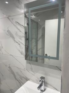 uma casa de banho branca com um lavatório e um espelho em Newly renovated studio in Acton em Londres
