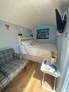 a small bedroom with a bed and a couch at Drakes Mead Retreat - Shepherd's Hut in Axminster