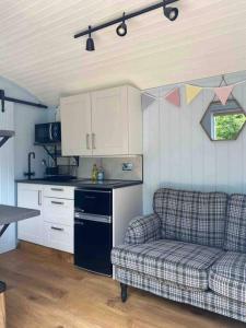 a living room with a couch and a kitchen at Drakes Mead Retreat - Shepherd's Hut in Axminster +19 photos