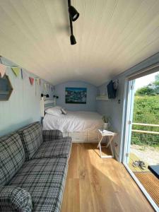 a bedroom with a bed and a couch in a room at Drakes Mead Retreat - Shepherd's Hut in Axminster