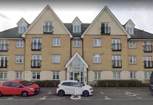 a large building with two cars parked in a parking lot at Maberic Housing II in Hounslow