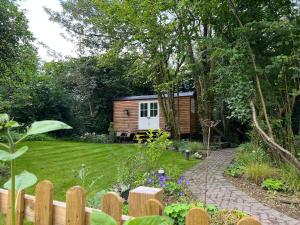 um jardim com uma pequena casa ao fundo em Tranquil Spot Shepherds Hut em Cinderford