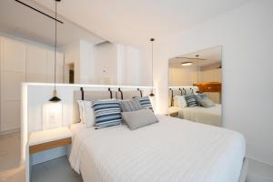 米克諾斯城的住宿－Arcs Boutique Villa Hotel，一间白色卧室,配有两张床和两面镜子