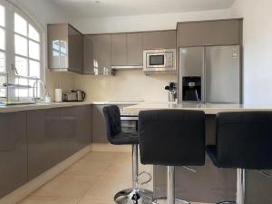 a kitchen with two bar stools and a counter top at VILLA ALICIA by JK Lanzarote in Puerto del Carmen