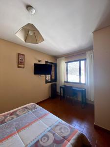 1 dormitorio con cama, mesa y TV en Open House Hostel en Mendoza