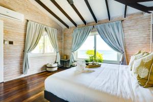 een slaapkamer met een groot wit bed en ramen bij Shaka Caye All inclusive Resort in Belize City