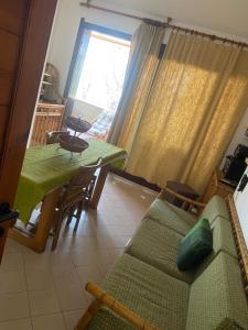 a living room with a green couch and a table at House pinus village in Forte Village