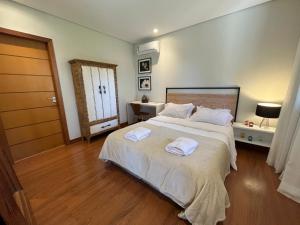 a bedroom with a large bed with two towels on it at Charmoso Chalet in Teresópolis