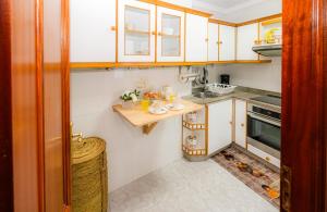 una pequeña cocina con armarios blancos y una encimera de madera. en El balcón de Barraña, en Boiro