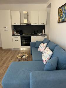 uma sala de estar com um sofá azul e uma cozinha em Azzurro Premium Apartment on Bulevard Bogoridi em Burgas