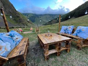 two wooden benches and a wooden table and chairs at Gudika • გუდიკა in Sno +10 photos