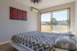 een slaapkamer met een bed en een groot raam bij Tamanaco Beach 1BDR apartment with balcony sea view and pool in Antibes