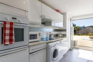 een witte keuken met een wasmachine en droger bij Tamanaco Beach 1BDR apartment with balcony sea view and pool in Antibes