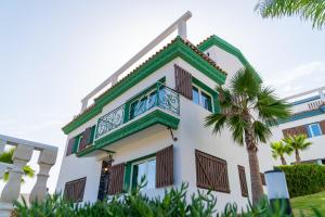 Oulad Akkou的住宿－CASA DEL TITO，带阳台和棕榈树的建筑