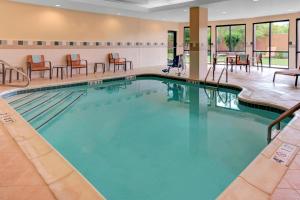 a pool in a hotel room with chairs and tables at Courtyard by Marriott Anniston Oxford in Oxford