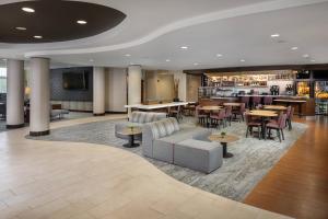 a hotel lobby with tables and chairs and a bar at Courtyard by Marriott Anniston Oxford in Oxford