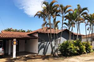 uma casa com palmeiras em frente em Casa de campo com piscina, mesa de bilhar e 3 quartos em Itanhandu