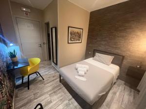 a hotel room with a bed and a yellow chair at Kalasó Design Guest House - Rome Airport in Fiumicino