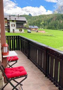 a balcony with two chairs and a table and a field at Casa Isotta Sappada in Sappada