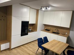 a kitchen with white cabinets and a wooden table and chairs at Nowoczesny Apartament Królowej Jadwigi in Radom