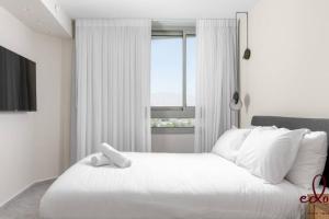 a white bed with a teddy bear on top of it at סוויטת View חדר שינה וסלון במתחם סי סייד in Eilat