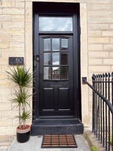 a black door on a building with two potted plants at Farsley Studio in Farsley