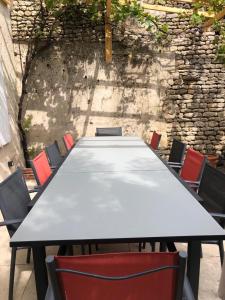 un lungo tavolo con sedie di fronte a un muro di pietra di Maison de vacances familiale au cœur du marais poitevin a Maillezais