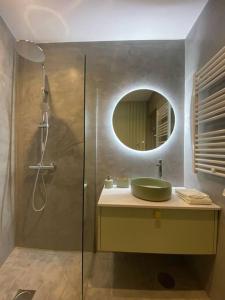 a bathroom with a sink and a shower with a mirror at Mercadoflat in Póvoa de Varzim