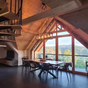 a dining room with a table and chairs and a large window at Luxury apartment with sauna and garden on the Czorsztyn lake in Kluszkowce