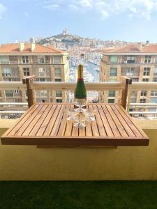 eine Flasche Wein auf einem Holztisch auf einem Balkon in der Unterkunft 3 bedroom apartment with beautiful view old port in Marseille