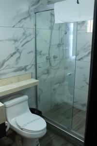 a bathroom with a toilet and a glass shower at Hotel Velario in Tijuana