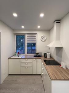 uma cozinha com armários brancos e um relógio na parede em Palūšės Apartment em Paluse