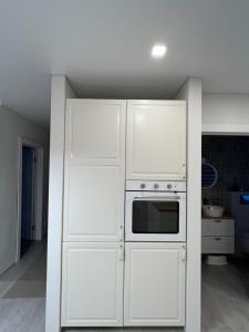 uma cozinha com armários brancos e um forno em Palūšės Apartment em Paluse