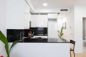 a kitchen with white cabinets and a black counter top at Cosmopolitan Loft y Malaga Beach in Málaga
