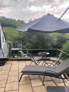 un tavolo e sedie su un balcone con ombrellone di Im Wald a Gleiszellen-Gleishorbach
