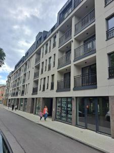 two people walking down a street in front of a building at Apartament Chabrowy ( centrum, garaż ) in Kielce