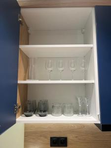 a cupboard filled with wine glasses and bowls at Apartament Chabrowy ( centrum, garaż ) in Kielce